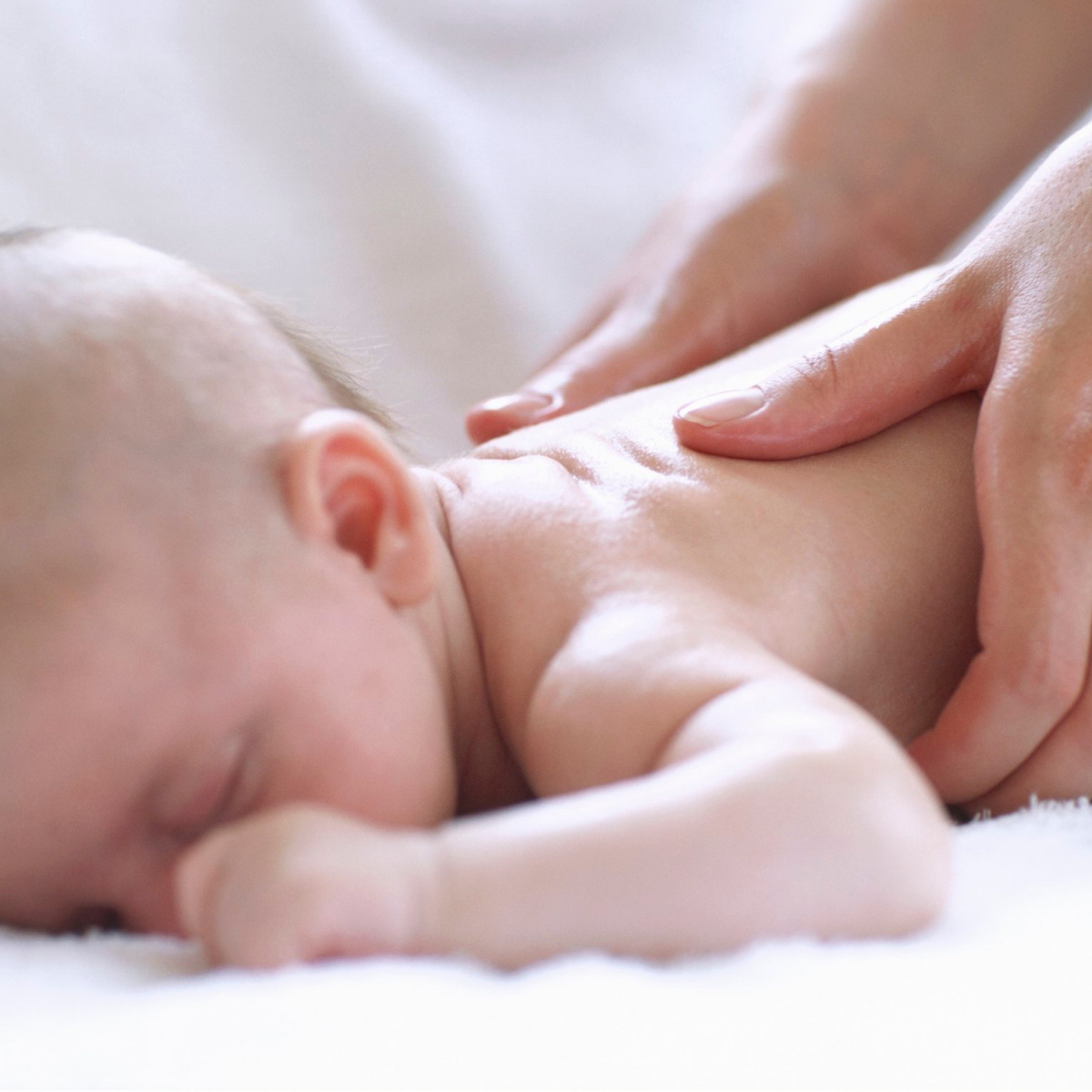 A parent performing the “I Love You” gentle baby massage technique on a baby’s abdomen to aid digestion.